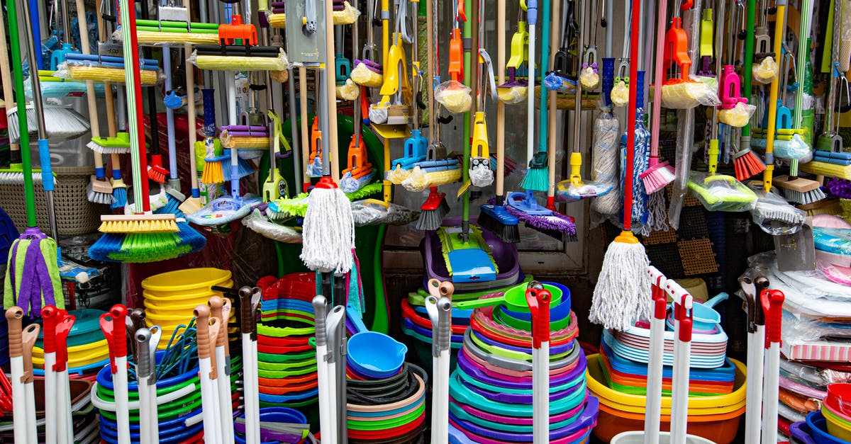 Check how many of that item I have while shopping? - Various colorful mops and brushes arranged with stack of plastic basins and bins in household goods supermarket