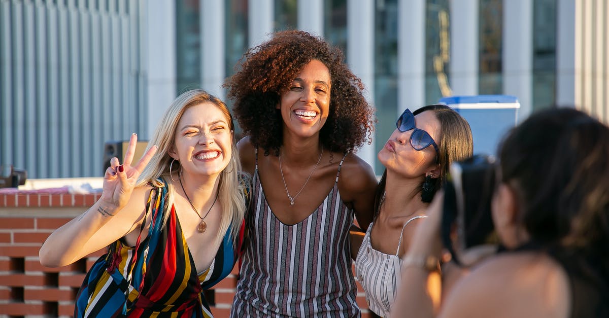 Civ 6 Capture City State - Unrecognizable female photographer taking picture of cheerful young multiracial female friends smiling and showing V sign during party on modern building rooftop