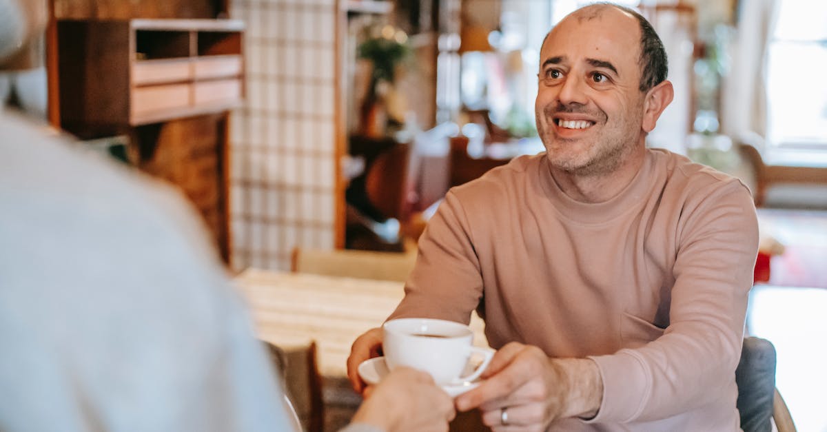 Clash of Clans: Take a break - Unrecognizable woman giving coffee cup to positive ethnic husband Clash of Clans: Take a break - Unrecognizable woman giving coffee cup to positive ethnic husband