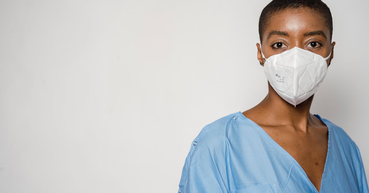 Combination for safe in Dishonored The Royal Physician mission - Serious African American female doctor in medical mask and blue uniform standing against white background