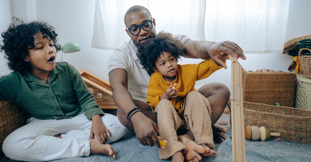 command creation: floor crafting help - African American man in casual wear and eyewear sitting on floor and playing with kids with curly hair