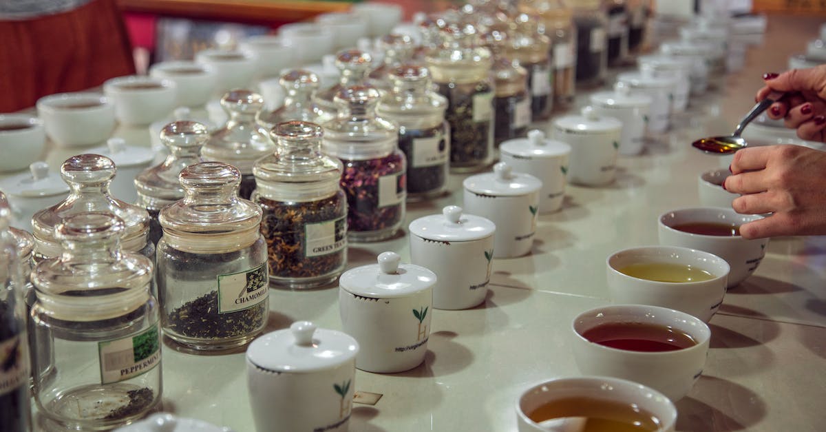 Commander Caius isn't there for the tasting ceremony during dampened spirits - Crop anonymous female with teaspoon standing near table with assorted aromatic teas served for tea tasting session