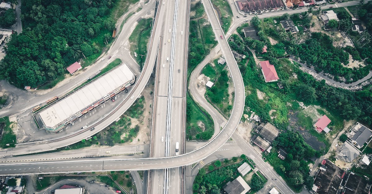 Connect to highway coming from outside city limits [duplicate] - Aerial view of asphalt roadway running among industrial building and residential houses located in suburb area surrounded with green trees