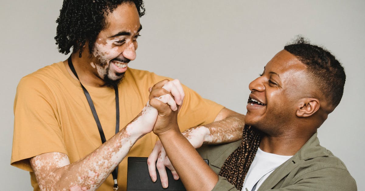 Consequences of partner approval/disapproval - Laughing black male colleagues clasping hands in excitement together