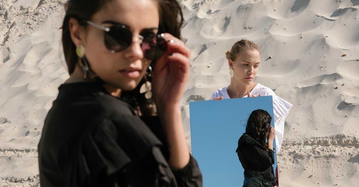 Contest is over. Can I see my ranking? - Young female rivals with mirror on sandy beach