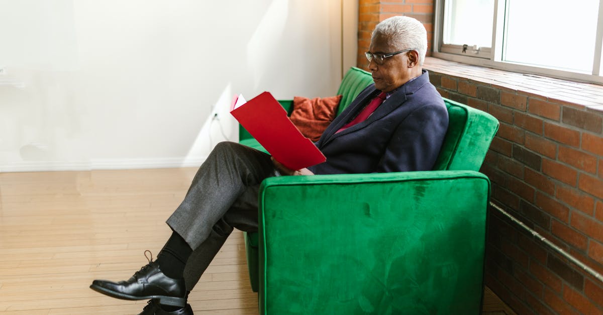 Continue from downloading folder - An Elderly Man in Blue Suit Sitting on the Couch while Looking on Red Folder