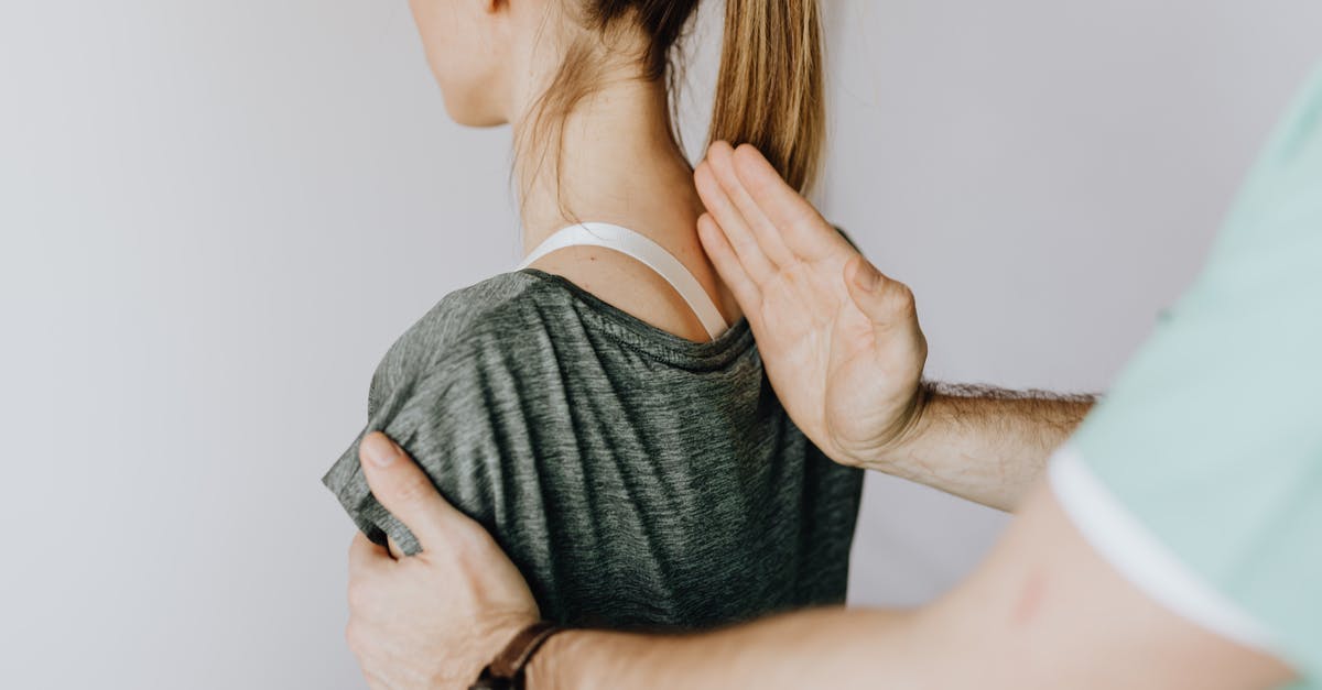 Control Landing on Stomach vs Back - Back view of crop unrecognizable osteopath in uniform and wristwatch checking up back of slim female patient in casual wear on white background Control Landing on Stomach vs Back - Back view of crop unrecognizable osteopath in uniform and wristwatch checking up back of slim female patient in casual wear on white background