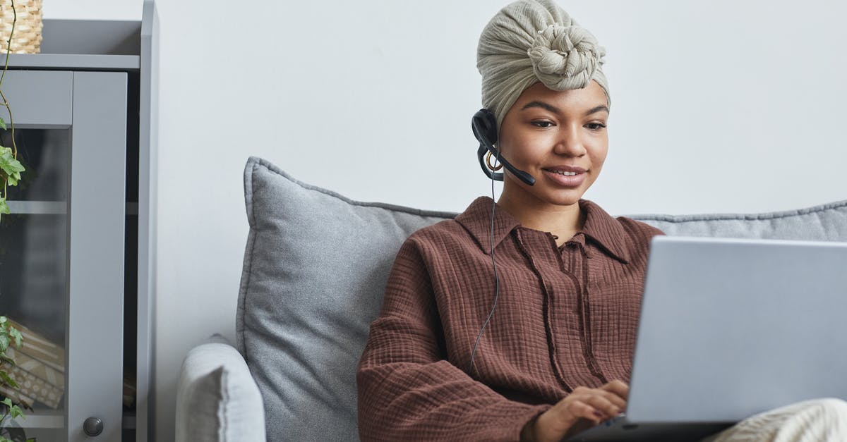Copycat Operator (Minor spoiler) - Focused African American female call agent with handsfree headset typing on netbook while sitting on couch near cupboard in light room Copycat Operator (Minor spoiler) - Focused African American female call agent with handsfree headset typing on netbook while sitting on couch near cupboard in light room