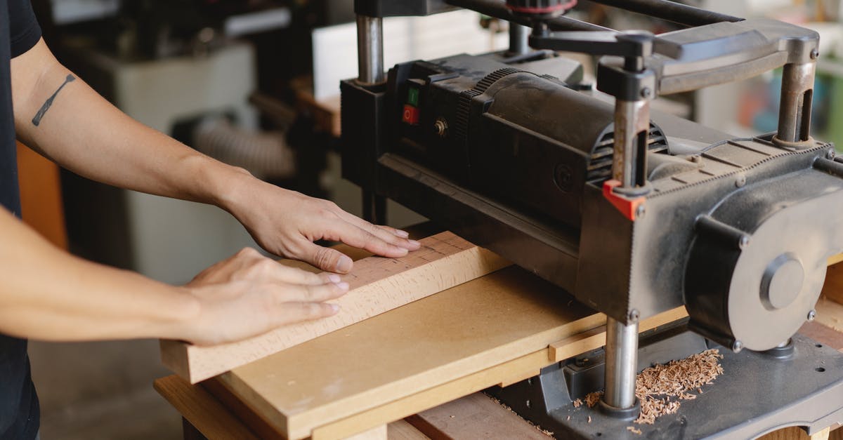 Cost efficient enchanting profession levelling - Crop anonymous tattooed woodworker leveling wooden plank on professional electric equipment in workshop in daylight Cost efficient enchanting profession levelling - Crop anonymous tattooed woodworker leveling wooden plank on professional electric equipment in workshop in daylight