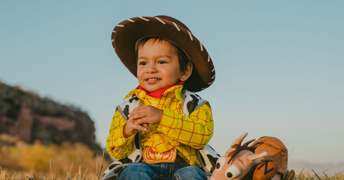 Cowboy with an odd accent - Child in Yellow and White Plaid Button Up Shirt and Blue Denim Jeans Sitting on Brown