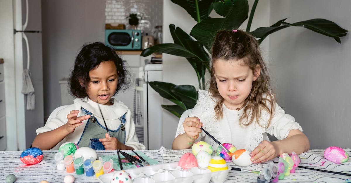 Creating a chest with a specific spawn egg inside - Concentrated multiracial girls painting white eggs with paintbrushes while sitting at table with paints in kitchen during Easter holiday at home Creating a chest with a specific spawn egg inside - Concentrated multiracial girls painting white eggs with paintbrushes while sitting at table with paints in kitchen during Easter holiday at home