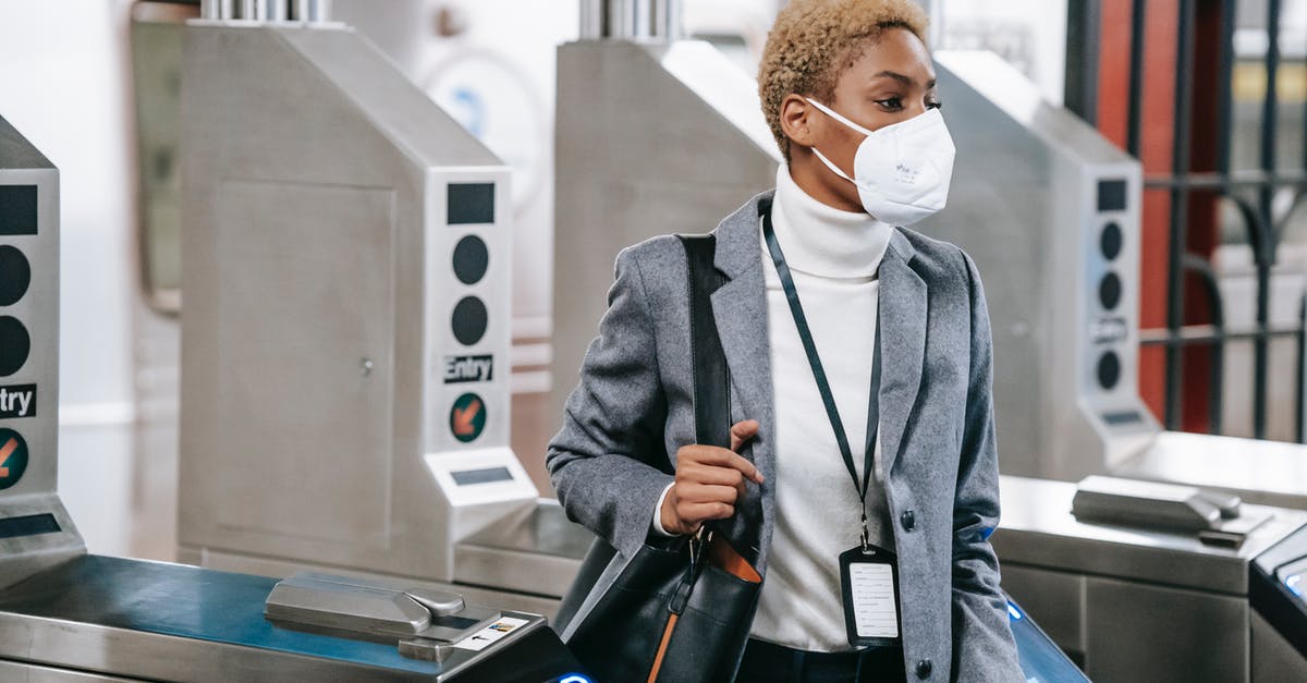 Creating a quest, problem with chips for pass weapons from subroom to subroom - Calm attractive African American female in stylish formal wear and protective mask passing through turnstile gates in underground station Creating a quest, problem with chips for pass weapons from subroom to subroom - Calm attractive African American female in stylish formal wear and protective mask passing through turnstile gates in underground station