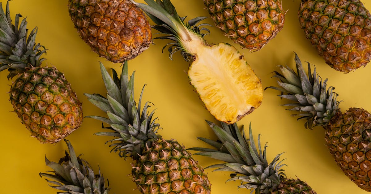 Crown summoned too many octopi - Top view composition of fresh pineapples with juicy colorful flesh placed on yellow background in light studio during ripening season Crown summoned too many octopi - Top view composition of fresh pineapples with juicy colorful flesh placed on yellow background in light studio during ripening season