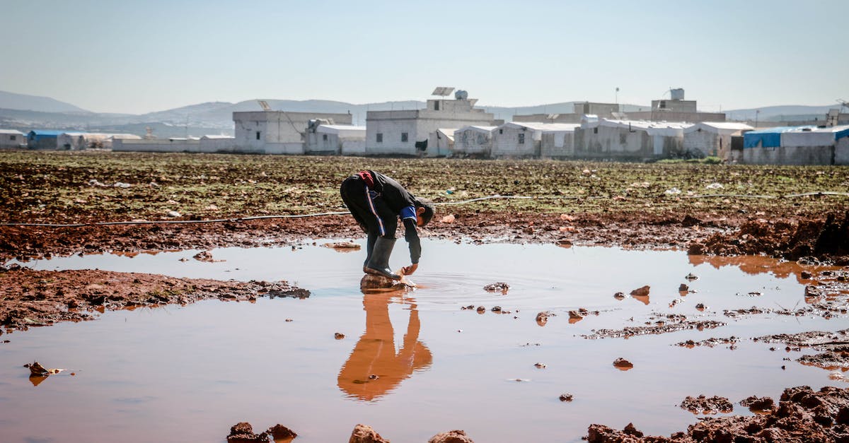 Cs GO Damage dealt, and died, over 400 - Full body of anonymous male pouring dirty water on legs in pond surrounded with settlement of refugee