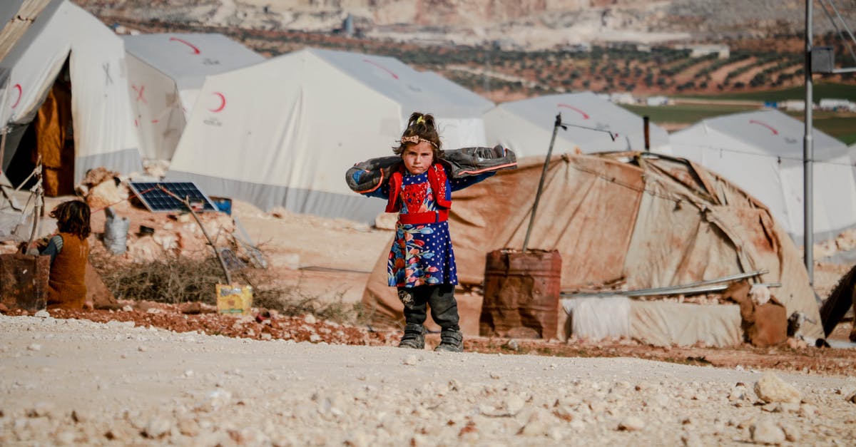 Damage mitigation in God of War series - Ethnic girl standing near refugee tents Damage mitigation in God of War series - Ethnic girl standing near refugee tents