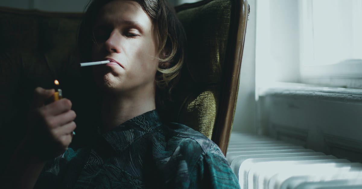 Dark Souls 2 coop/invading problem - Young guy lighting cigarette and smoking while sitting in armchair near window at home Dark Souls 2 coop/invading problem - Young guy lighting cigarette and smoking while sitting in armchair near window at home