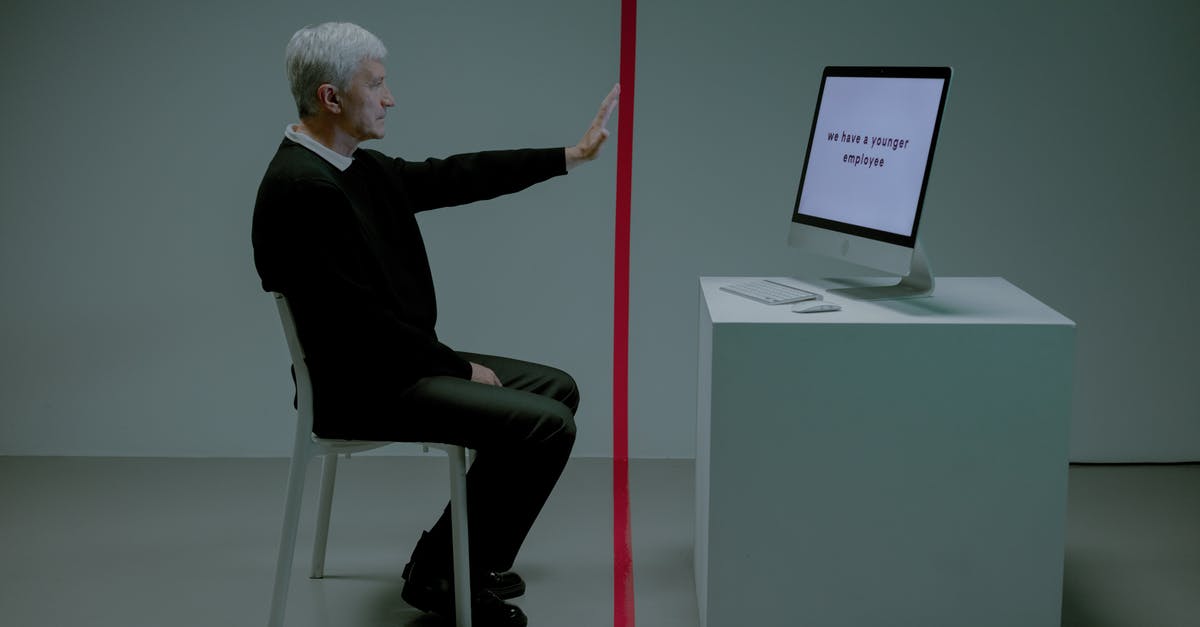 Deino before the E4 - Senior adult man sitting before computer separated from him by red line Deino before the E4 - Senior adult man sitting before computer separated from him by red line