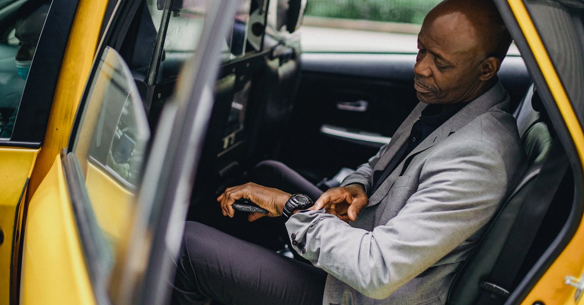 Delay redstone with commands [duplicate] - Serious black businessman checking time on wristwatch in taxi