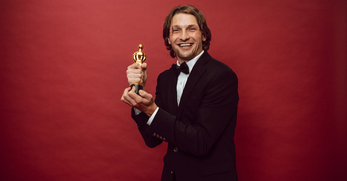 Determining the best starter in Pokemon Red? - A Happy Man in a Black Suit Holding His Trophy Determining the best starter in Pokemon Red? - A Happy Man in a Black Suit Holding His Trophy