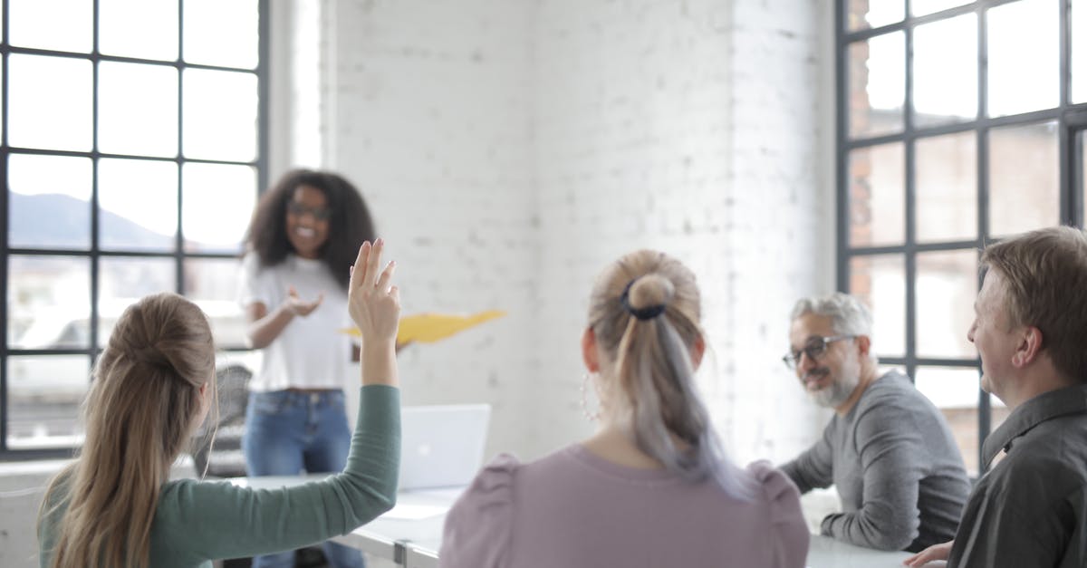 Difference between Age of Empires 2 HD and the original Age of Empires 2 - Female worker in casual wear raising hand for asking question during corporate diverse group meeting in modern office boardroom