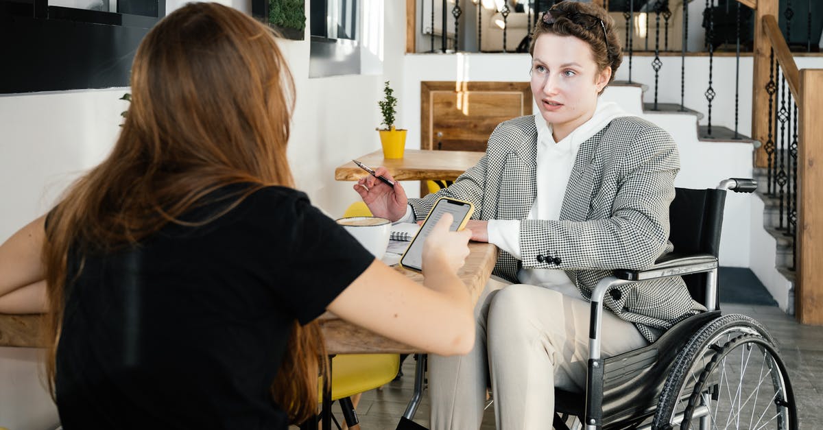 Disable Factorio GUI info tooltip - Concentrated female using wheelchair talking to coworker during coffee break in modern cafeteria