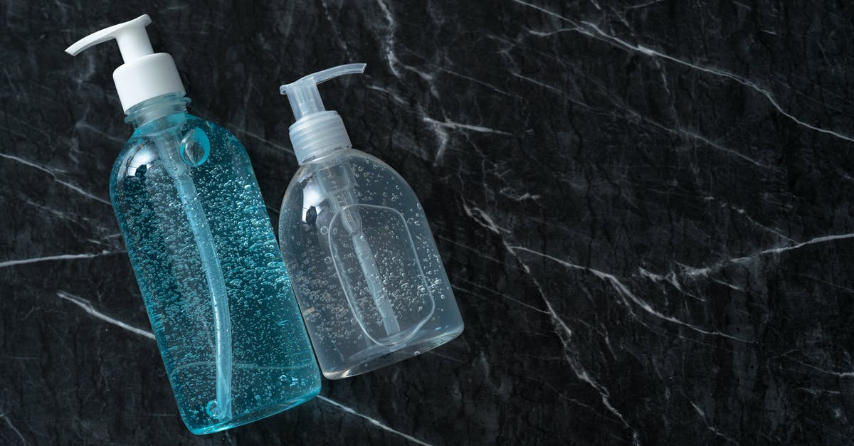 Dispenser stops shooting items when full - From above of transparent dispensers with antiseptic gels on marble table with cracks during COVID 19 pandemic