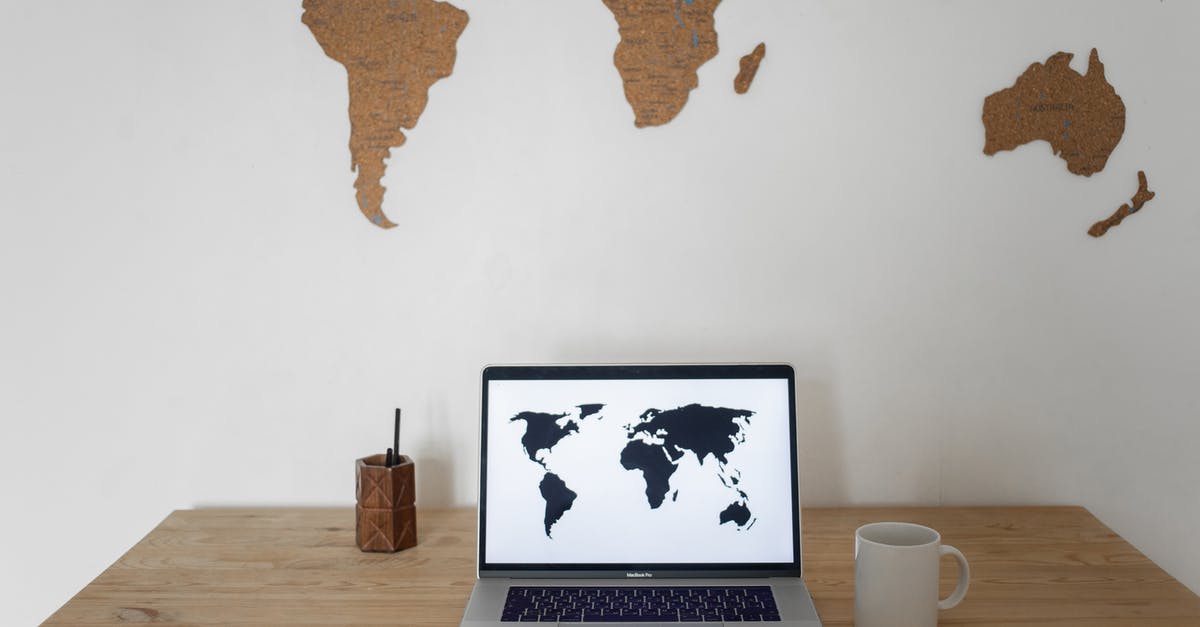 Display pokemons on the map with delay - Black world map on laptop screen and ceramic cup with pen container placed on table against silhouettes of continents Display pokemons on the map with delay - Black world map on laptop screen and ceramic cup with pen container placed on table against silhouettes of continents