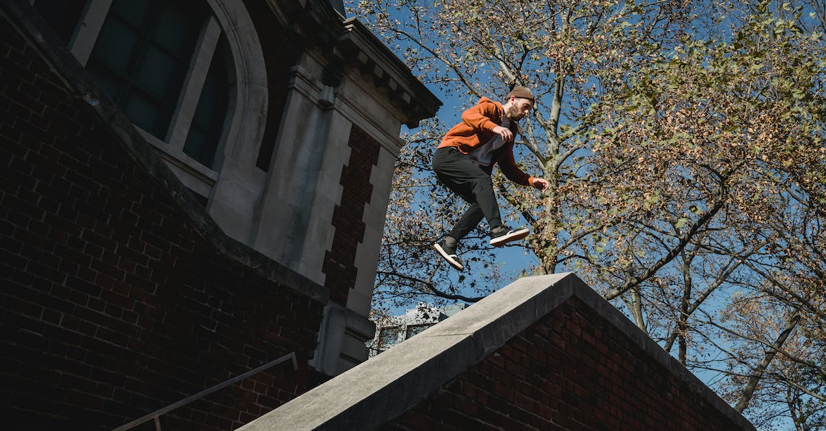 Do Adrenaline Skills have separate adrenaline bars? - From below full body fit sporty male tracer in hoodie and hat jumping over staircase and brick building parapet on sunny day