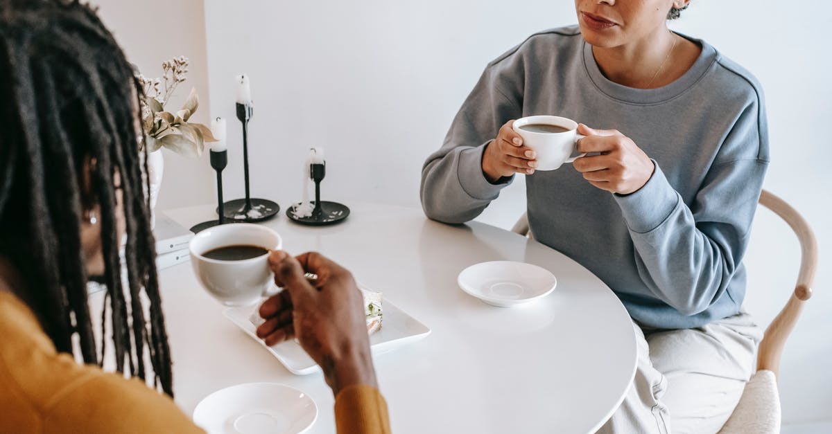 Do any heroes share romantic relationships with other heroes? - From above of crop pensive Hispanic female in casual clothes sitting at light table and drinking coffee with African American boyfriend in modern cafe