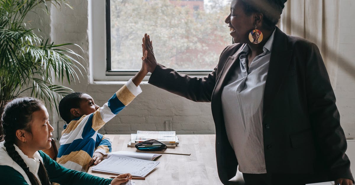 Do Civs on the same team share abilities? - Side view of smiling black boy giving high five to teacher while sitting with diverse classmate girl at desk in classroom