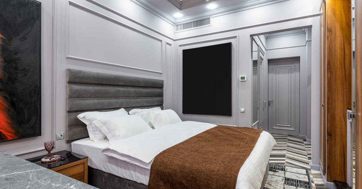 Do doors provide any cover at all? - Modern hotel room with soft pillows and cover on bed between entrance door and table with glass