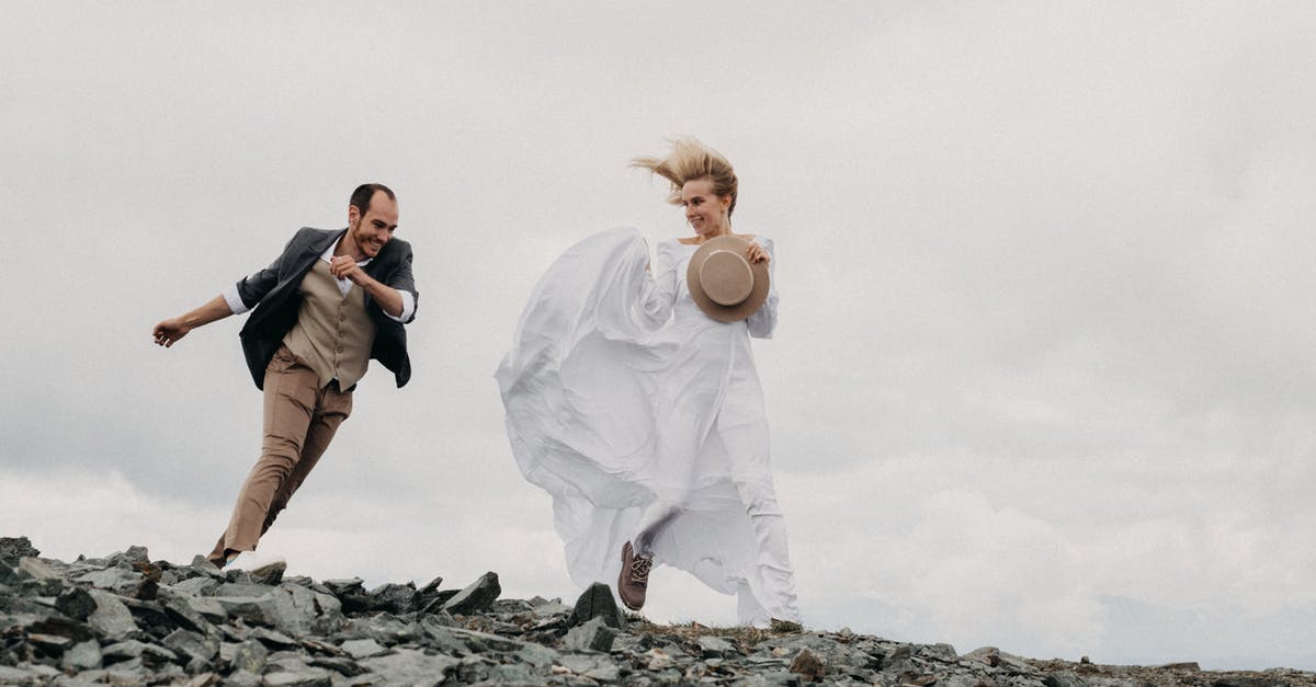 Do expeditions have an expiration date? - Full body of cheerful loving groom and bride in long white dress running on rough stones under cloudy gray sky