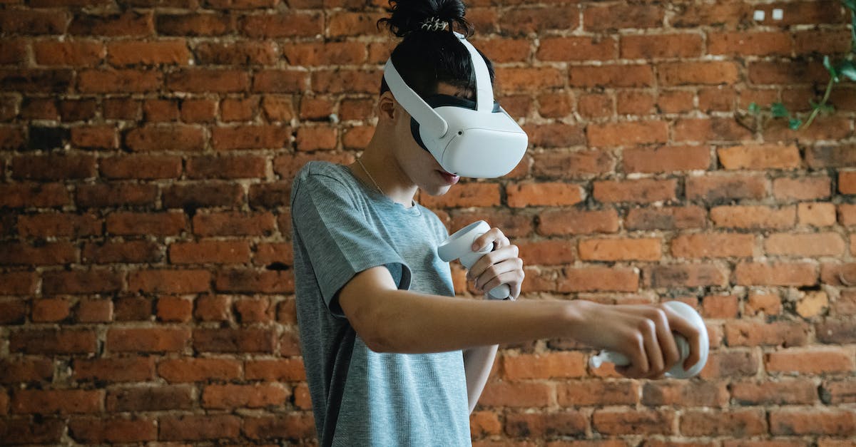 Do experience orbs disappear if you don't collect them? - Side view of teen boy in t shirt with VR headset and controllers playing game near brick wall