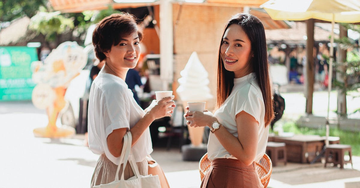 Do forage items appear over time or daily? - Back view glad young ethnic females in stylish summer clothes standing with cups of aromatic hot drinks in sunny outdoor market and looking at camera over shoulder