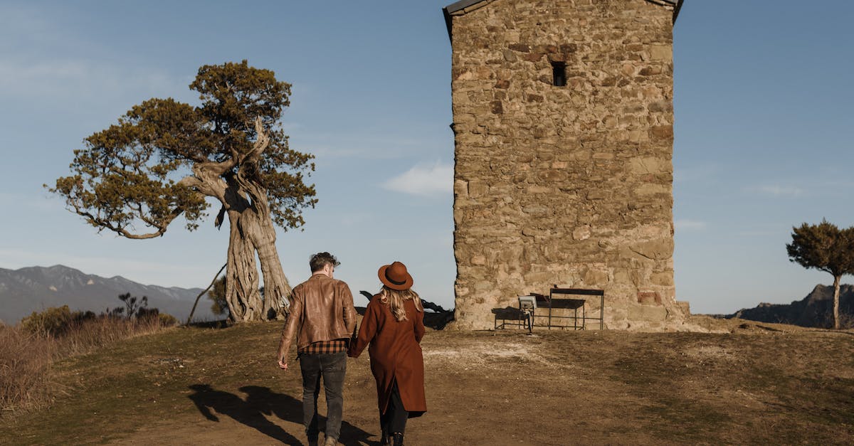 Do goblins activate spring traps? - Faceless stylish couple walking towards ancient tower in picturesque nature