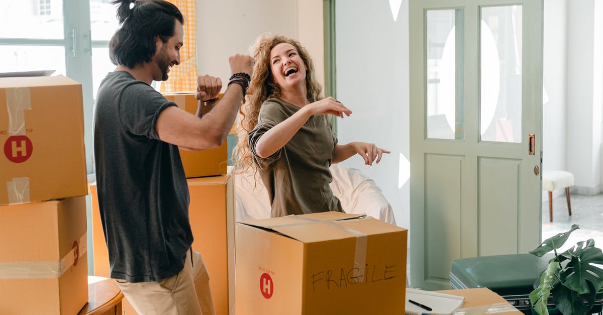Do I ever run out of new recruits? - Cheerful laughing couple in casual clothes having fun and dancing together while unpacking carton boxes after moving into new contemporary apartment
