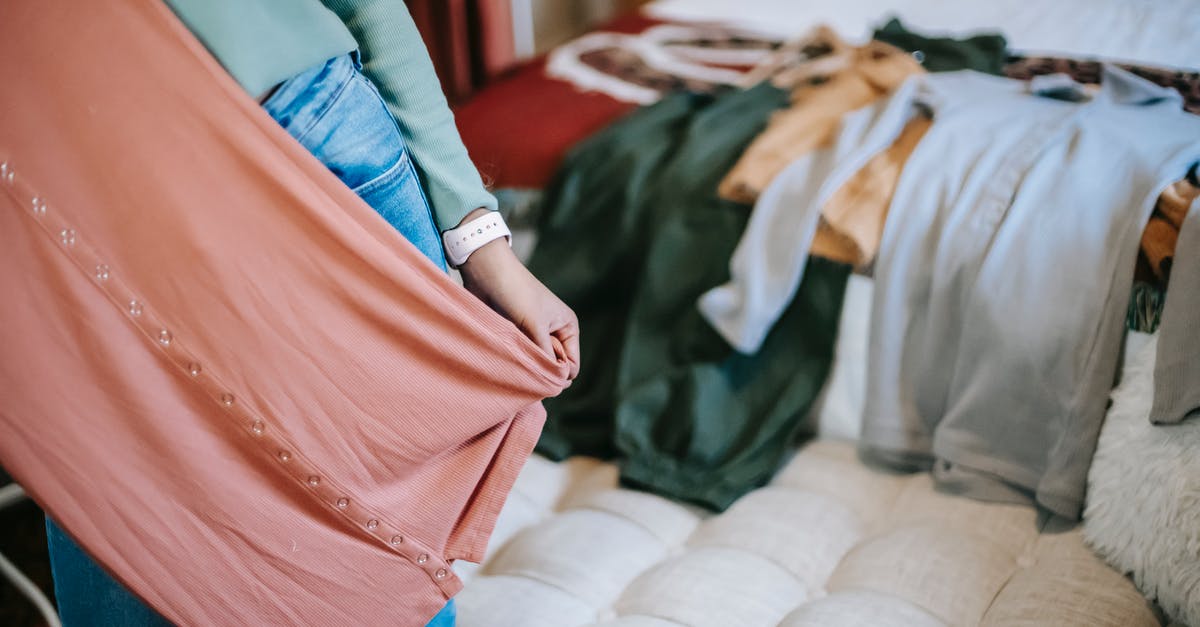 Do I have to select new quirks? - Crop anonymous woman in casual clothes demonstrating pink dress while selecting clothes while standing in bright bedroom near couch and bed with wardrobe at home Do I have to select new quirks? - Crop anonymous woman in casual clothes demonstrating pink dress while selecting clothes while standing in bright bedroom near couch and bed with wardrobe at home