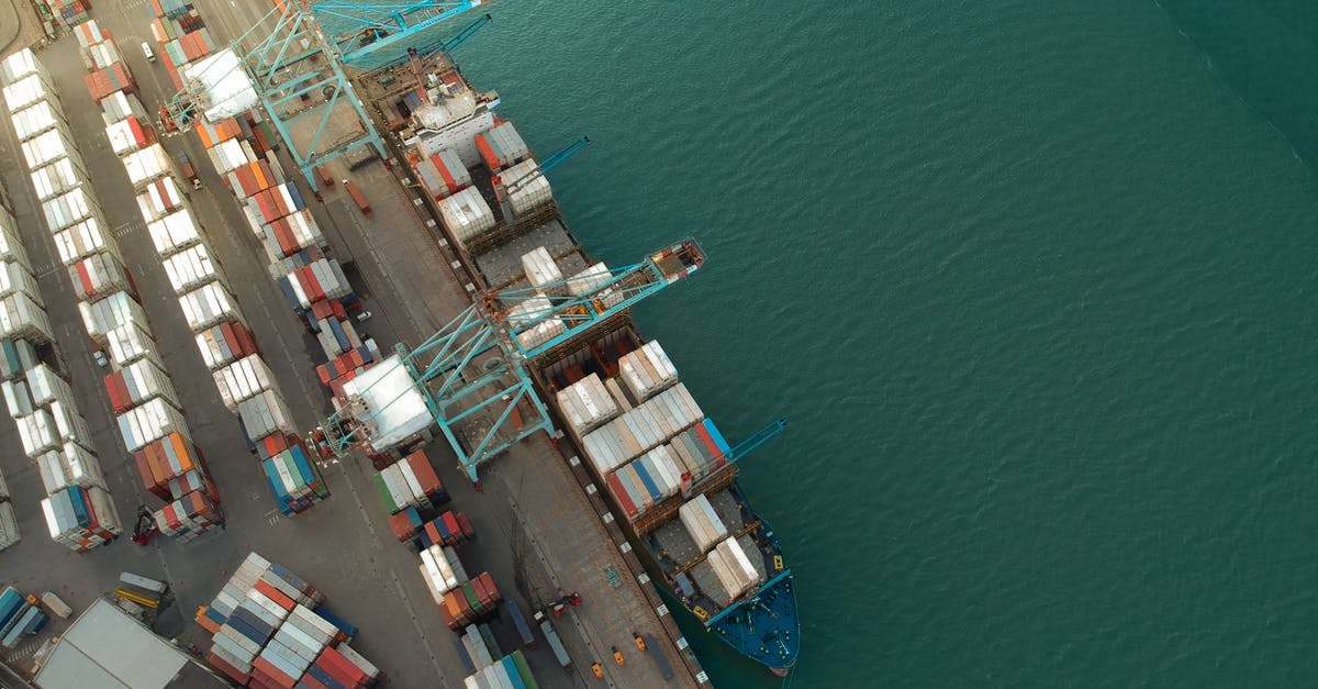 Do logistic drones and vessels carry goods roundtrip? - Top view of harbor with containers and cargo ships located near calm rippling sea water
