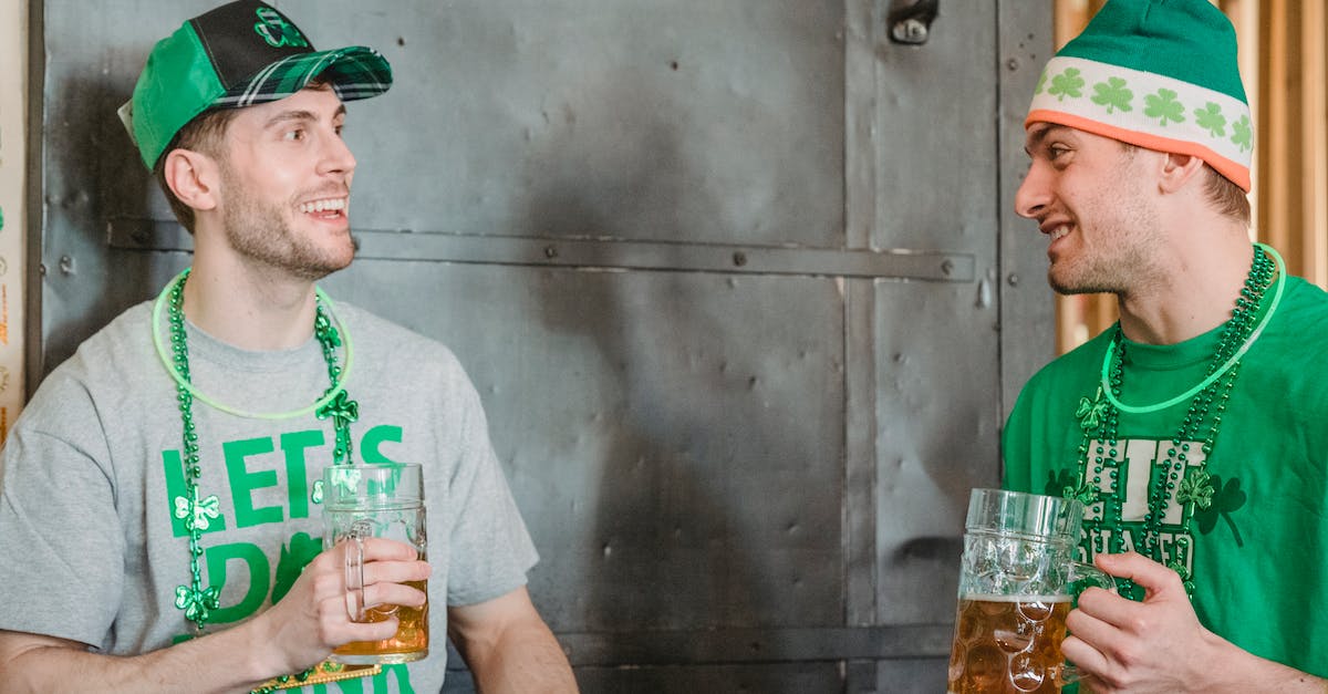 Do Luck-J and Mug synergise? - Cheerful unshaven friends in green hat with symbols of Saint Patricks Day wearing neon green glow stick and necklace decorated with shamrock and green beads talking and drinking ale