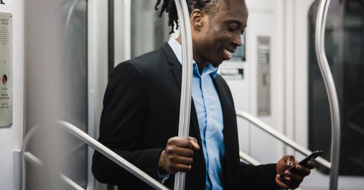 Do office workers like public transport? - Cheerful black man surfing net on mobile on subway train Do office workers like public transport? - Cheerful black man surfing net on mobile on subway train