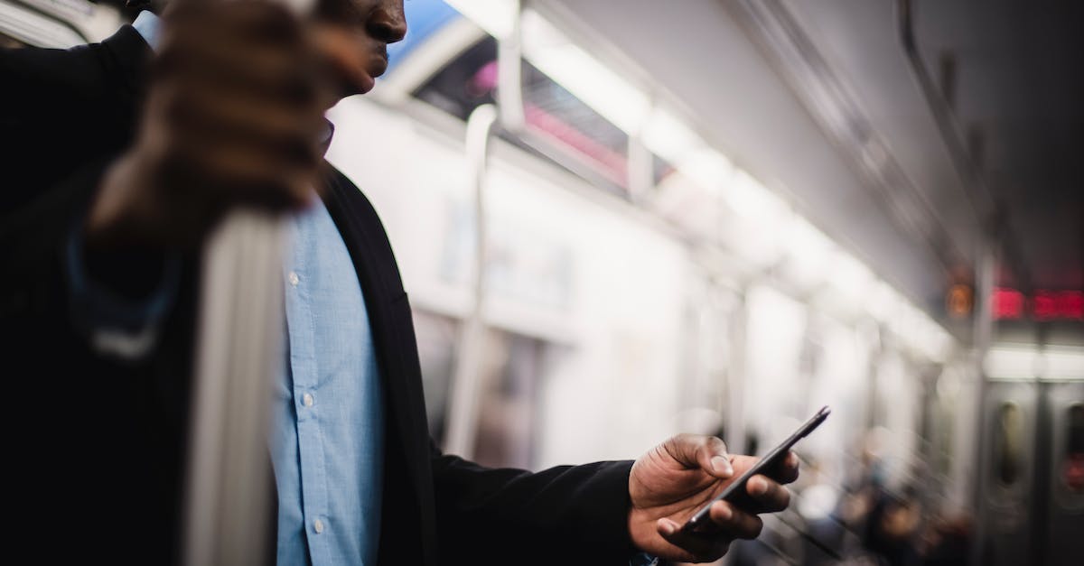 Do office workers like public transport? - Black man using mobile while commuting by train Do office workers like public transport? - Black man using mobile while commuting by train