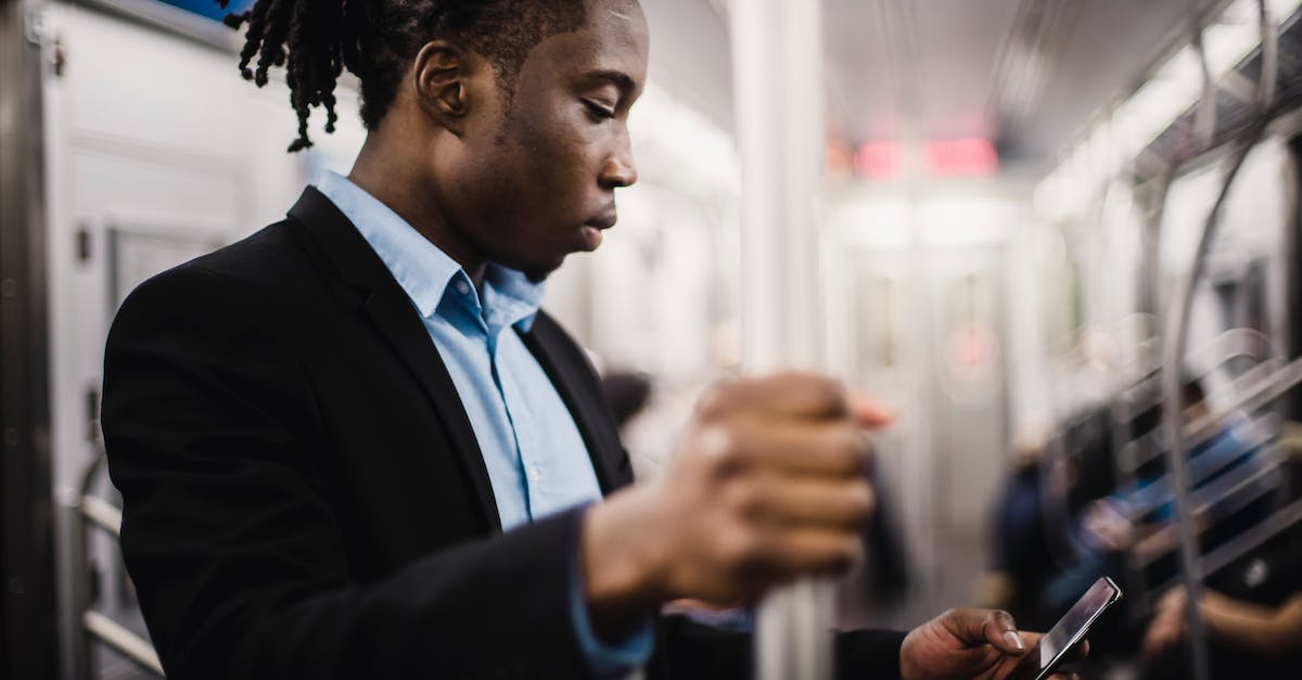 Do office workers like public transport? - Young African American man using smartphone on train Do office workers like public transport? - Young African American man using smartphone on train