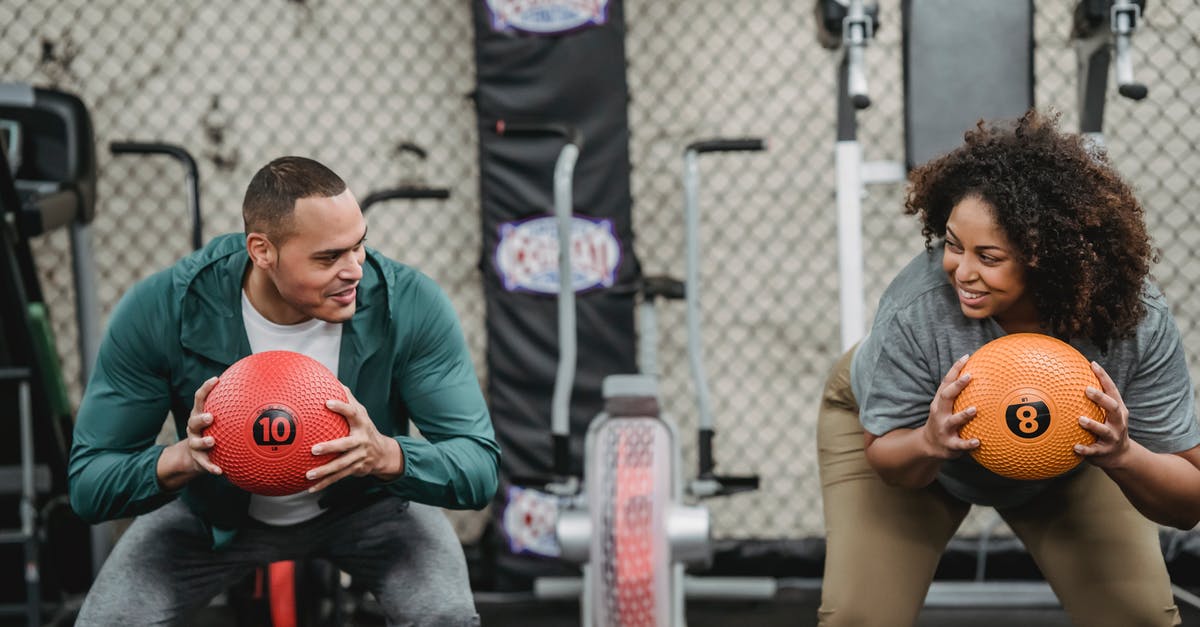 Do Power Troopers revive each other? - Diverse man and plump woman exercising with bright balls in sport club with gym equipment