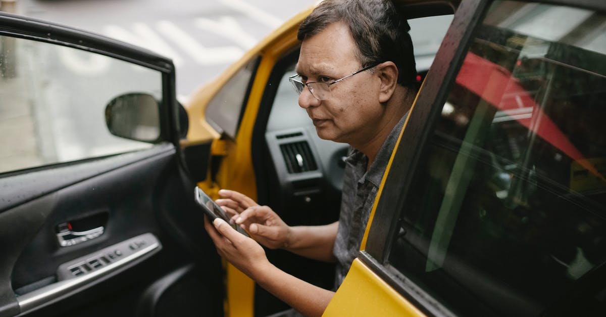 Do the heroes I use for Tap Battles matter? - Crop Asian man sitting in parked yellow taxi car with open door and using smartphone while looking away