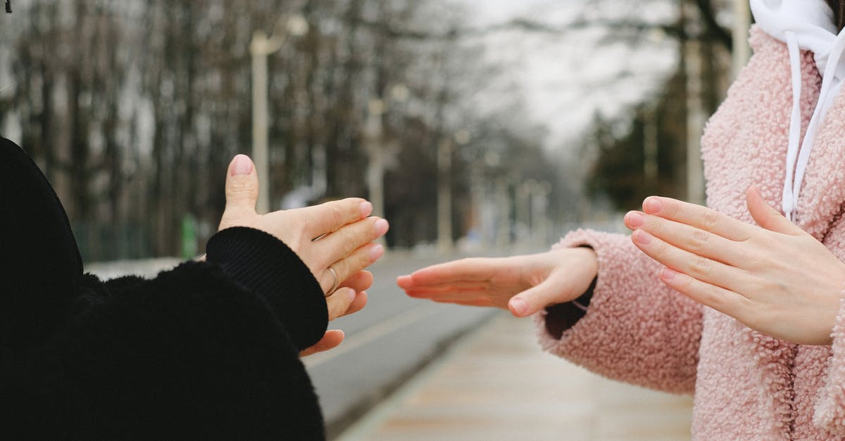 Do the residents of Facade talk in a language that can be understood? - Crop anonymous people in outerwear standing in park on blurred background in winter and using sign language