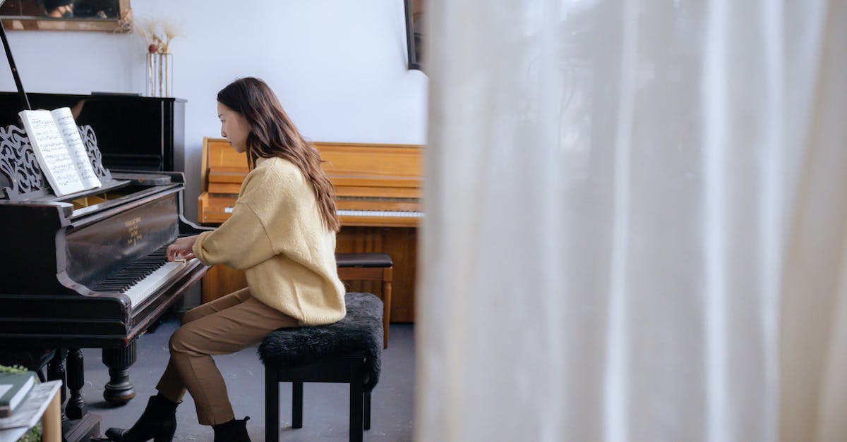 Do you need a key to play Diablo 2 on multiple accounts? - Full body of concentrated Asian lady in casual clothes and boots on high heels sitting on stool and gently touching piano keys and attentively looking at music book