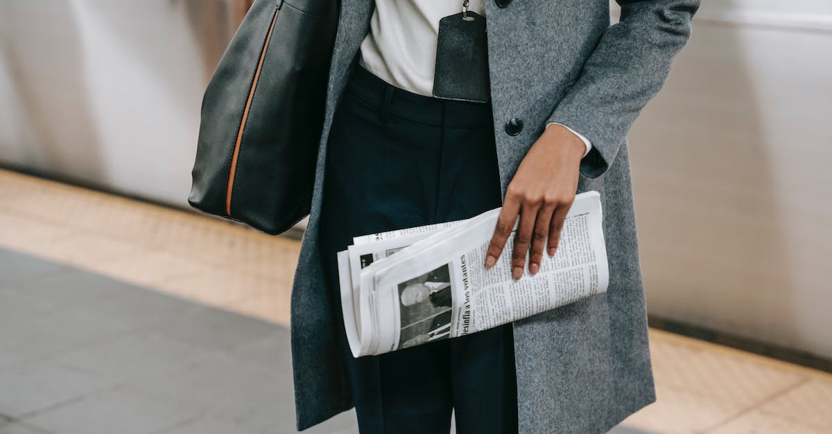 Does a villager only ask you to add a police station (or other public works) when they approach you? - From above of crop anonymous female employee in elegant outfit and name tag standing on platform of metro station with newspaper in hand