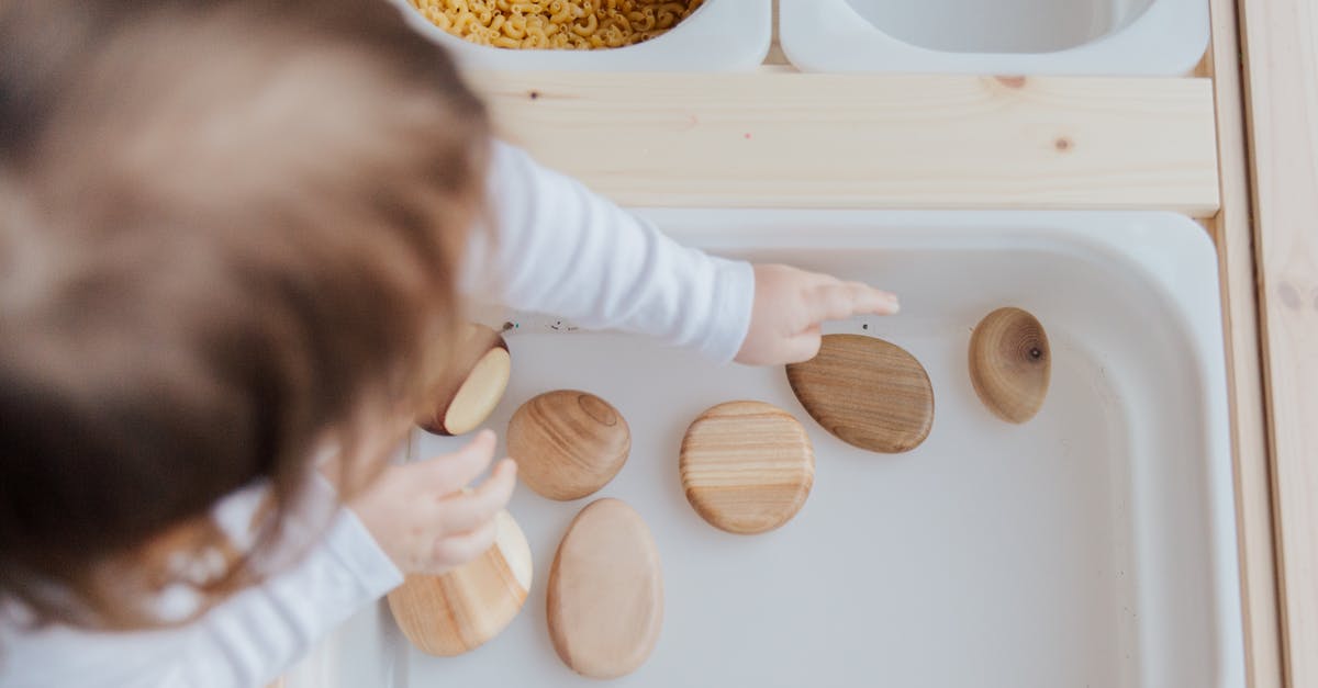 Does anyone know from which game this screenshot is? - Crop anonymous child getting brown stones from white container at home