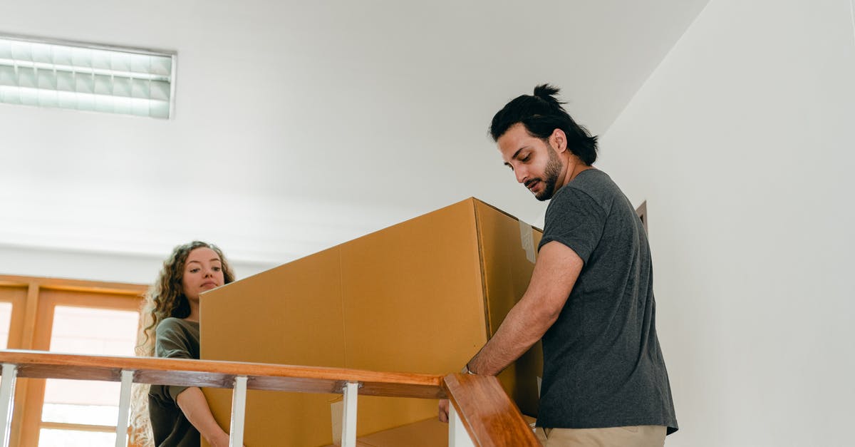 Does being in human form help with item discovery? - From below of couple in casual clothes carrying big carton box together while moving packed personal items into new apartment
