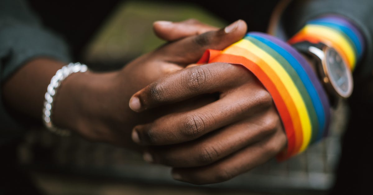 Does being left handed or right handed affect a mobs attributes? - Crop anonymous African American homosexual male wearing colorful rainbow ribbon on arm while sitting on street with hands clasped